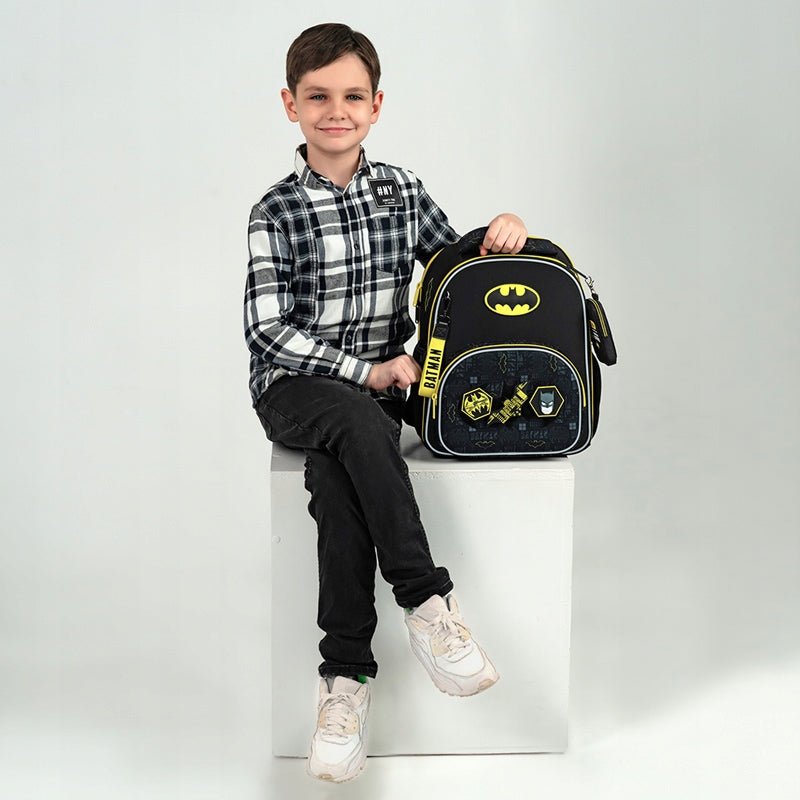 Chłopiec siedzi z plecakiem szkolnym Batman, ergonomiczny plecak dla dzieci do szkoły 130-145 cm