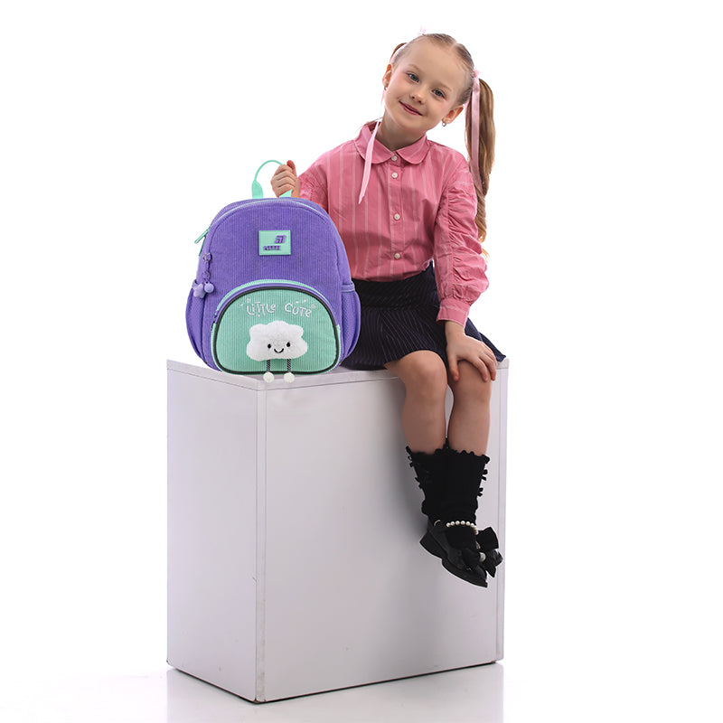 Mała modelka siedząca obok fioletowego plecaka, prezentująca proporcje produktu.