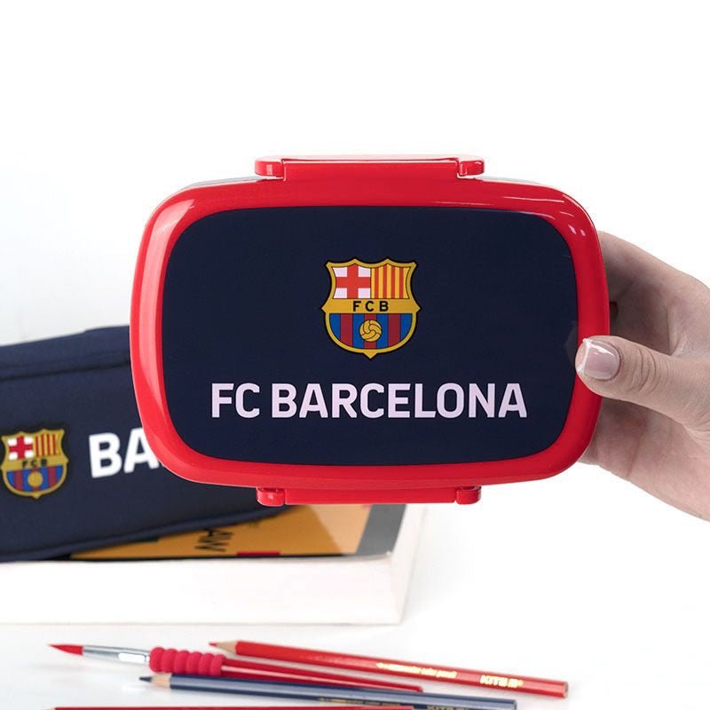 Lunchbox FC Barcelona trzymany w dłoni, szkolny pojemnik na śniadanie na tle zeszytu i długopisów