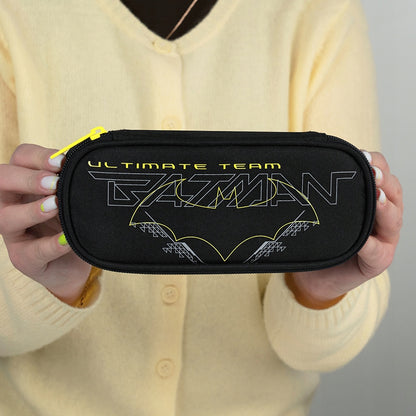 Zamknięty piórnik z logo Batmana trzymany przez ucznia.